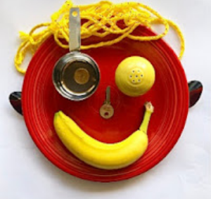Face made using a plate with things like a banana, yarn and a key for facial features