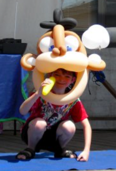 Child wearing a monkey balloon head sculpture